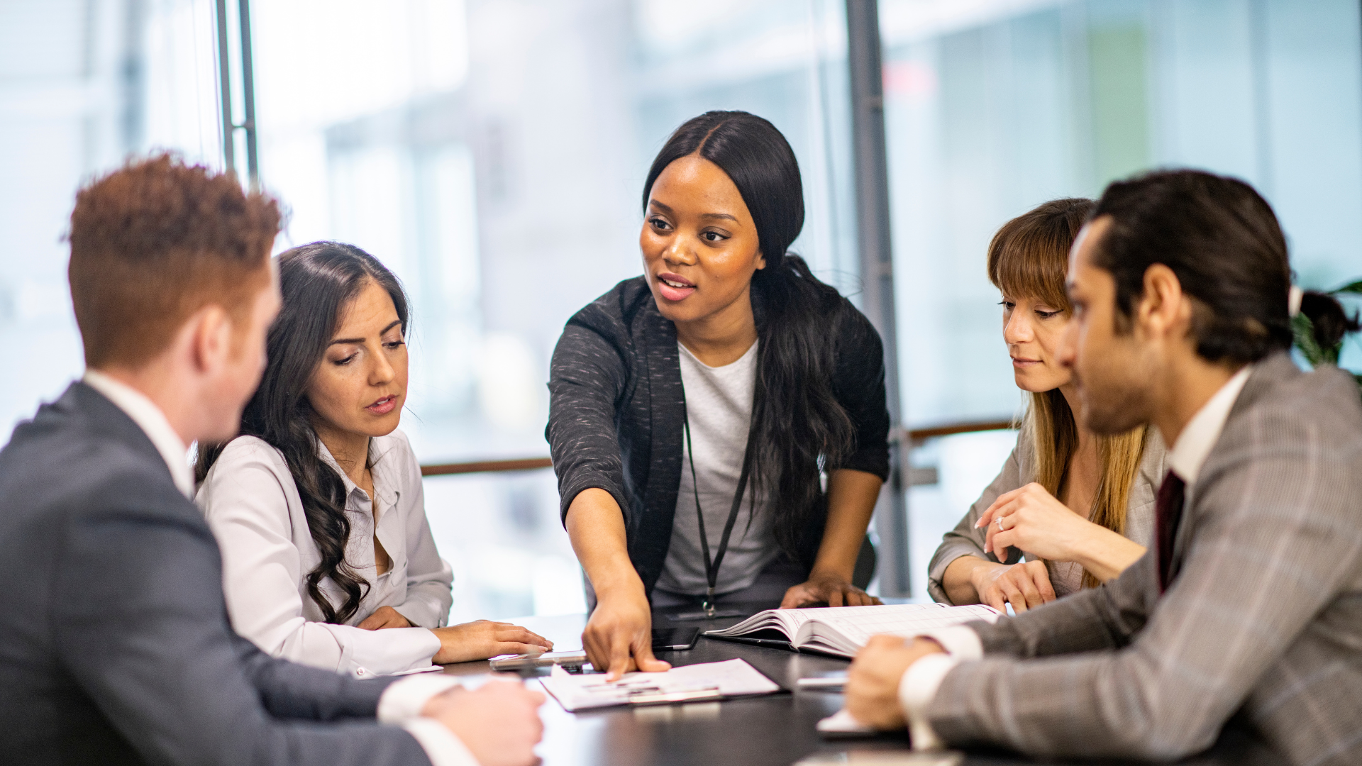 A group of professionals engaged in a meeting, discussing documents at a conference table in a modern office setting.