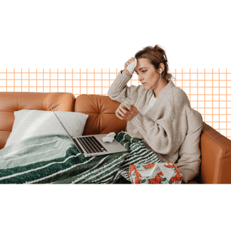 Person wrapped in a blanket on a couch, holding medicine and wiping their forehead, with a laptop and tissues nearby.