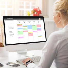 A person sits at a desk looking at a computer screen displaying a colorful calendar and to-do list for September.