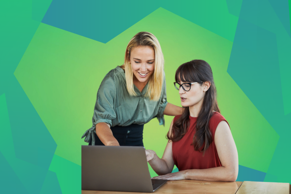 Two individuals collaborate at a laptop on a wooden desk, surrounded by a vibrant green geometric background.